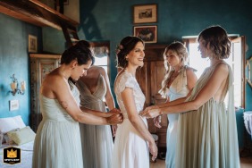 The bride smiles as her friends help with final dress preparations at Tenuta Il Galletto, a wedding venue in Italy
